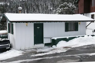 a white building with a green door in the snow at Fawn Valley Inn- Cabana apts in Estes Park