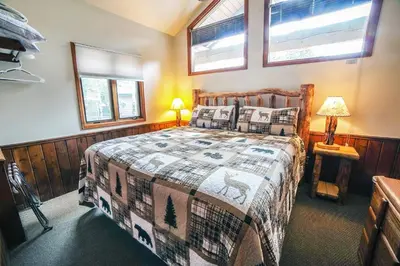 a bedroom with a bed and two windows at Sunnyside Knoll- 5 cabin in Estes Park