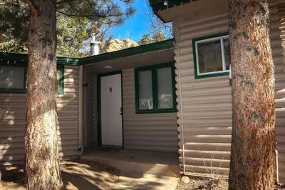 a garage with a white door and two trees at Sunnyside Knoll- 5 cabin in Estes Park