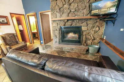 a leather couch in a living room with a fireplace at Timber Creek Chalets- 7 cabin in Estes Park