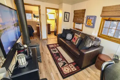 a living room with a leather couch and a wood stove at Lazy R Cottages- 5 cabin in Estes Park