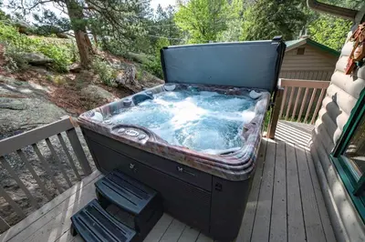 a hot tub sitting on a deck with two chairs at Sunnyside Knoll- 7 cabin in Estes Park