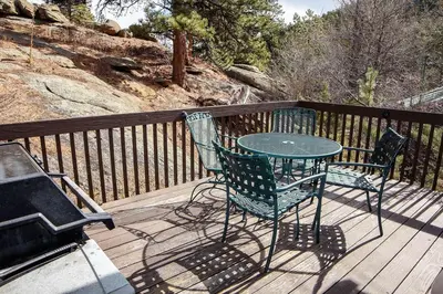 a table and chairs on a deck next to a grill at Sunnyside Knoll- 7 cabin in Estes Park
