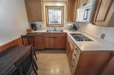 a kitchen with wooden cabinets and a sink and a table at Sunnyside Knoll- 8 cabin in Estes Park