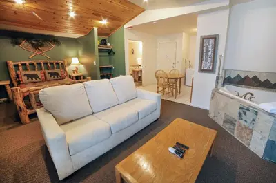 a living room with a couch and a bedroom at Fawn Valley Inn- 104 condo in Estes Park