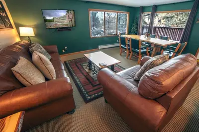 a living room with two leather couches and a table at Timber Creek Chalets- 14 chalet in Estes Park
