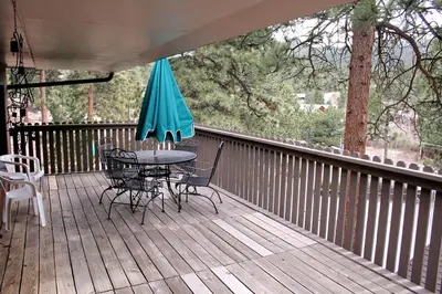 a table and chairs on a deck with an umbrella at Timber Creek Chalets- 14 chalet in Estes Park