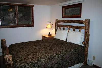 a bedroom with a bed and a lamp on a table at Timber Creek Chalets- 14 chalet in Estes Park