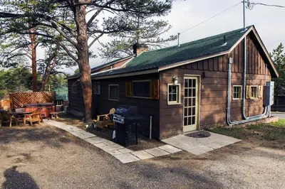a small cabin with a porch and a grill at Triple R Cottages- 8 cabin in Estes Park