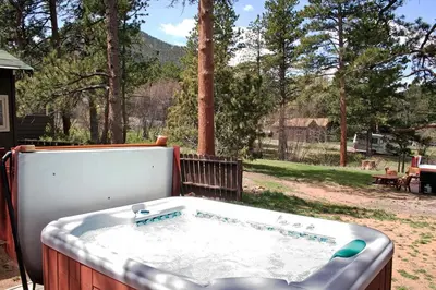 a hot tub on a patio with a view of trees at Triple R Cottages- 8 cabin in Estes Park