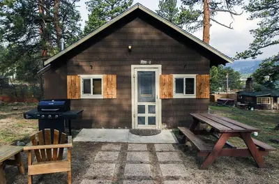 a tiny house with a picnic table and a grill at Triple R Cottages- 2 cabin in Estes Park