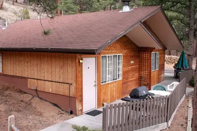 a small cabin with a grill in front of it at Timber Creek Chalets- 11 chalet in Estes Park