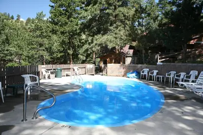 a large blue pool with chairs in a backyard at Timber Creek Chalets- 11 chalet in Estes Park