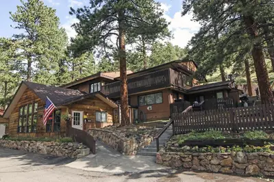 a log cabin with an american flag in front of it at Timber Creek Chalets- 11 chalet in Estes Park