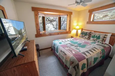 a bedroom with a bed and a flat screen tv at Sunnyside Knoll- 9 cabin in Estes Park