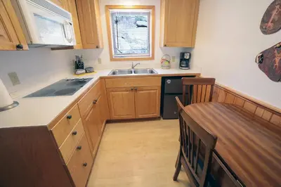 a kitchen with wooden cabinets and a sink and a table at Sunnyside Knoll- 9 cabin in Estes Park