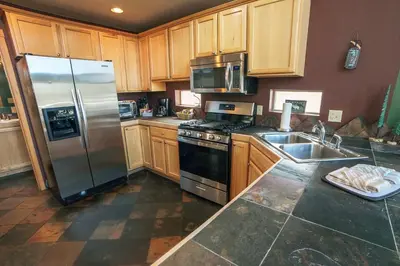 a kitchen with wooden cabinets and a stainless steel refrigerator at Lazy R Cottages- 16A cabin in Estes Park