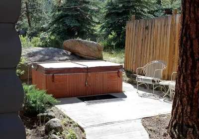 a wooden deck with a grill and a chair in a yard at Sunnyside Knoll- 6 cabin in Estes Park