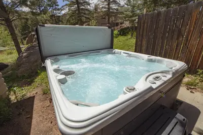 a hot tub sitting in a yard next to a fence at Sunnyside Knoll- 6 cabin in Estes Park