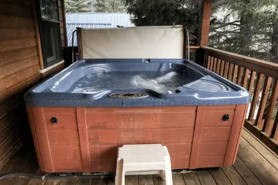 a hot tub on a deck with a stool at Lawn Lane B - #3383 in Estes Park