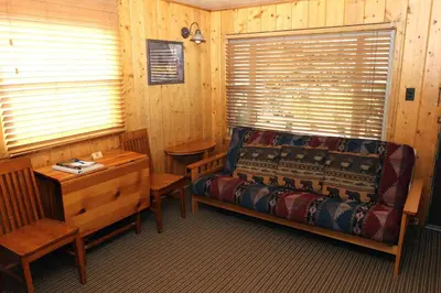 a bedroom with a bed and a table and a window at Lazy R Cottages- 1 apts in Estes Park