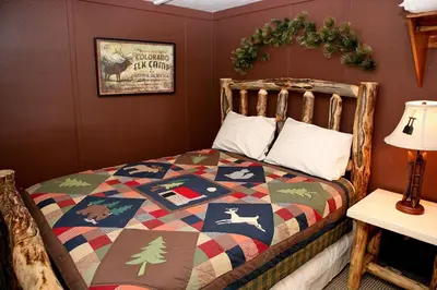 a bedroom with a bed with a christmas quilt on it at Triple R Cottages- 5 cabin in Estes Park