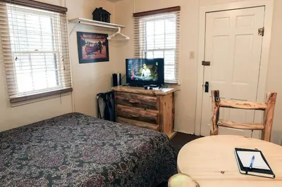 a bedroom with a bed and a tv and a table at Triple R Cottages- 7 cabin in Estes Park