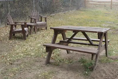 three wooden benches and a picnic table in a field at Triple R Cottages- 7 cabin in Estes Park