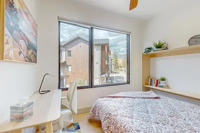 a bedroom with a bed and a desk and a window at Alpine Vista Haven in Silverthorne