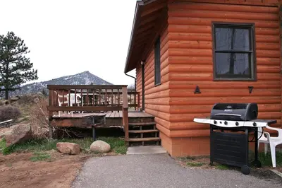 a log cabin with a grill and a porch at Lazy R Cottages- 7A cabin in Estes Park