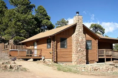 a log cabin with a stone chimney and a porch at Lazy R Cottages- 17 cabin in Estes Park