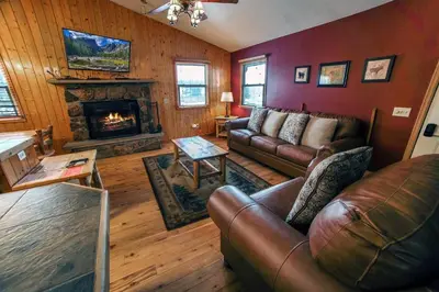 a living room with leather couches and a fireplace at Lazy R Cottages- 17 cabin in Estes Park