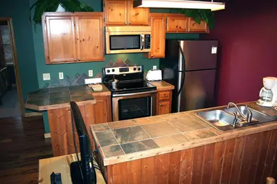 a kitchen with wooden cabinets and a stainless steel refrigerator at Lazy R Cottages- 17 cabin in Estes Park