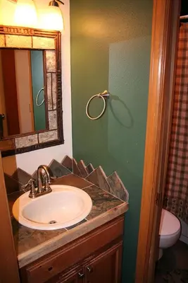 a bathroom with a sink and a mirror and a toilet at Lazy R Cottages- 17 cabin in Estes Park