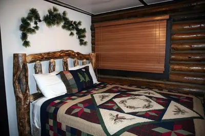 a bedroom with a wooden bed with a quilt on it at Triple R Cottages- 1 cabin in Estes Park