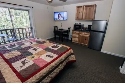 a bedroom with a bed and a kitchen with a refrigerator at Fawn Valley Inn- 293 condo in Estes Park