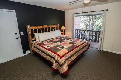a bedroom with a large bed and a balcony at Fawn Valley Inn- 293 condo in Estes Park