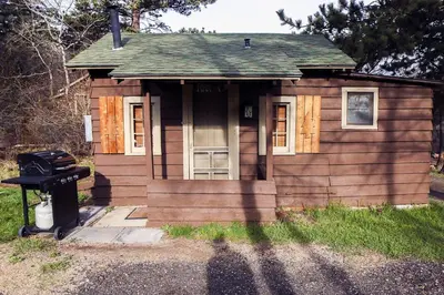 a small wooden house with a door and a grill at Triple R Cottages- 4 cabin in Estes Park