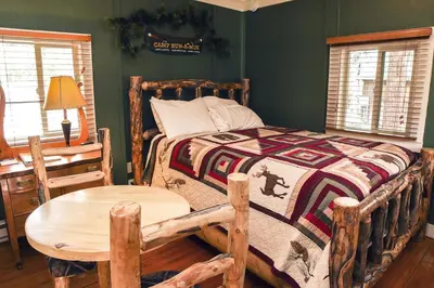 a bedroom with a wooden bed and a wooden table at Triple R Cottages- 4 cabin in Estes Park