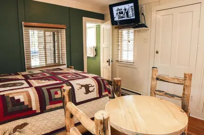 a bedroom with a bed and a table and a tv at Triple R Cottages- 4 cabin in Estes Park