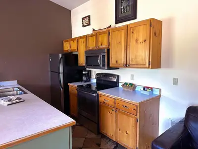a kitchen with wooden cabinets and a black refrigerator at Lazy R Cottages- 14 cabin in Estes Park