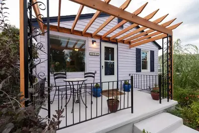 a tiny house with a pergola on a deck at Private Bungalow with Kids Playset in Denver