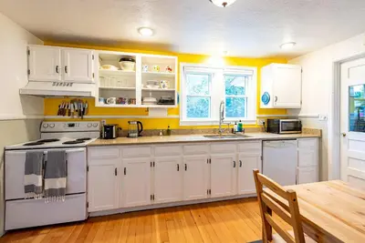 a kitchen with white cabinets and a wooden table at Private Bungalow with Kids Playset in Denver