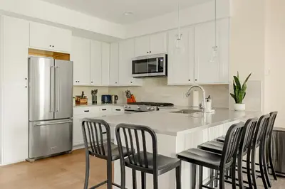 a kitchen with white cabinets and a kitchen island with chairs at Heart of Olde Town - Urban Retreat - 95 Walk Score in Arvada