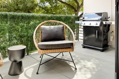 a wicker chair with a pillow sitting in front of a grill at Heart of Olde Town - Urban Retreat - 95 Walk Score in Arvada
