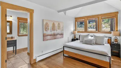a bedroom with a bed and a desk and windows at Moose Tracks Lodge in Breckenridge