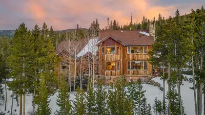 a large wooden house in the woods in the snow at Alpenglow Peaks Lodge in Breckenridge