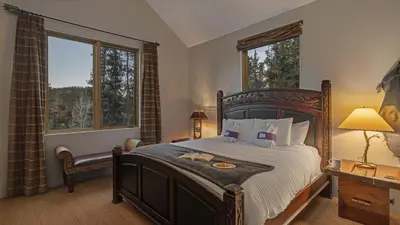 a bedroom with a large bed and two windows at Alpenglow Peaks Lodge in Breckenridge