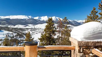 a view of snow covered mountains from a wooden bench at Point View Place in Breckenridge