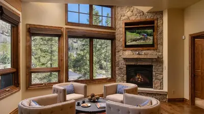 a living room with a stone fireplace and windows at Winterfell Estates in Breckenridge